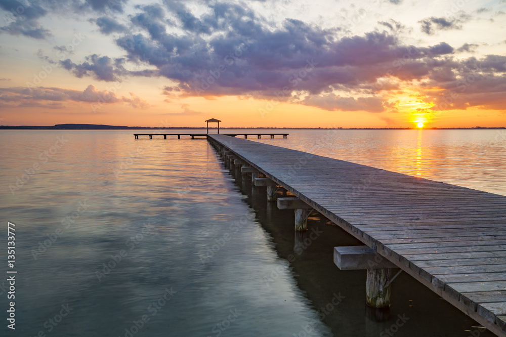 wooden pier overlooking the lake, the beautiful evening sky, colored by the setting sun
