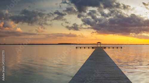 Fototapeta Naklejka Na Ścianę i Meble -  wooden pier overlooking the lake, the beautiful evening sky, colored by the setting sun
