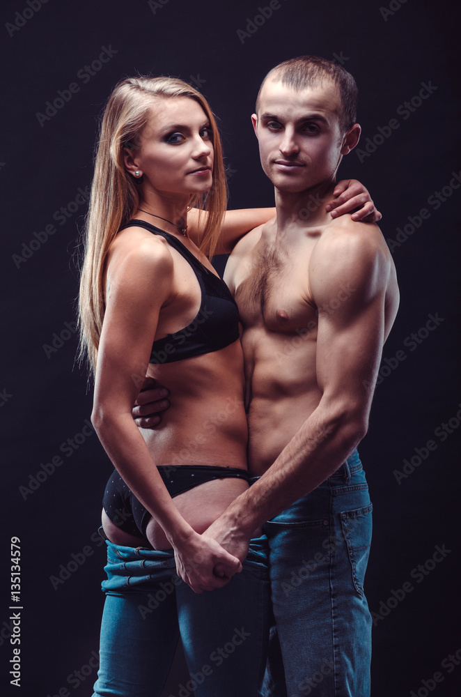 Sexy couple in jeans. Boyfriend and girlfriend embracing in the dark.
