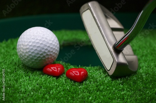Putting golf ball and hearts with putter
