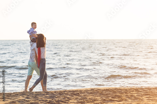 Fototapeta Naklejka Na Ścianę i Meble -  happy young family have fun on beach run and jump at sunset