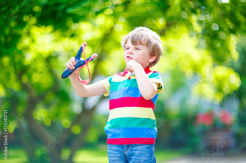 little kid boy shooting wooden slingshot