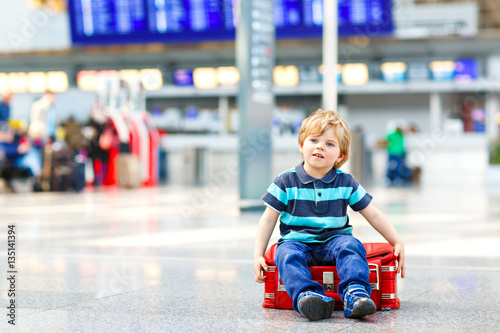 Little kid boy going on vacations trip with suitcase at airport