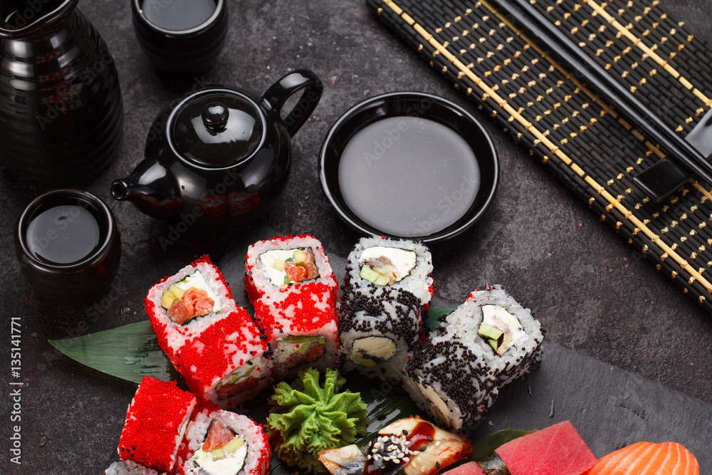 Japanese cuisine. Sushi set on a stone plate and black concrete background. Japanese cuisine. Sushi set on a stone plate and black concrete background.