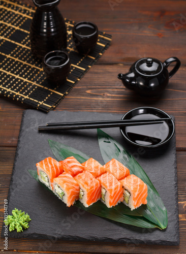 Salmon sushi roll on a stone plate and wooden background.