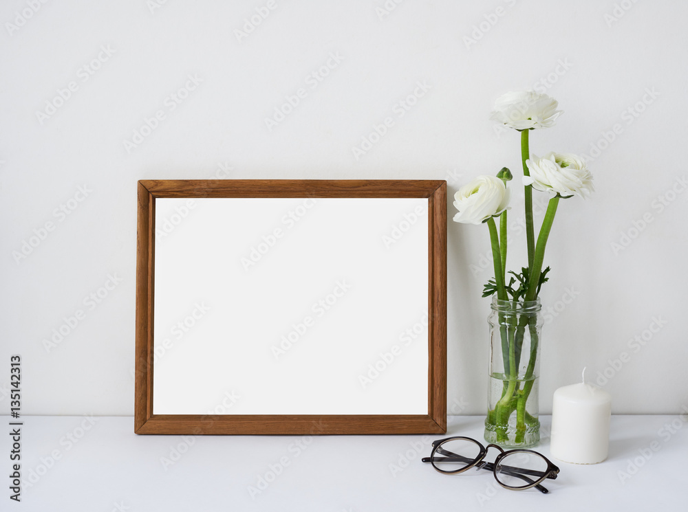 Interior poster mock up with horizontal wooden empty frame, bouquet of white flowers ranunculus, candle and glasses. Empty space for design presentation or your work