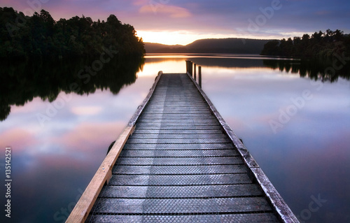 Fototapeta Naklejka Na Ścianę i Meble -  New Zealand, South Island - Wooden jetty on still lake reflectin