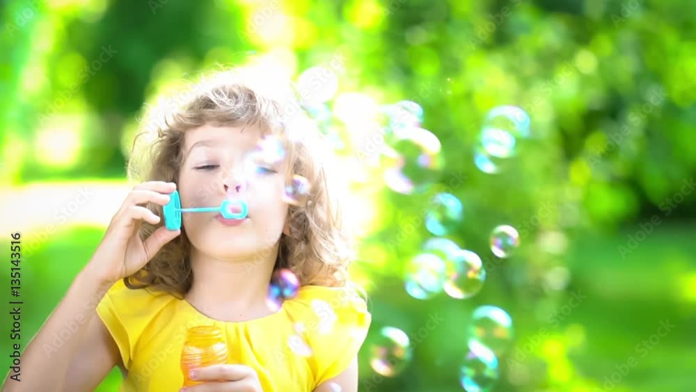Happy child blowing soap bubbles in spring park. Kid having fun outdoors. Imagination and freedom concept. Slow motion from 120 fps Happy child blowing soap bubbles in spring park. Kid having fun outdoors. Imagination and freedom concept. Slow motion from 120 fps