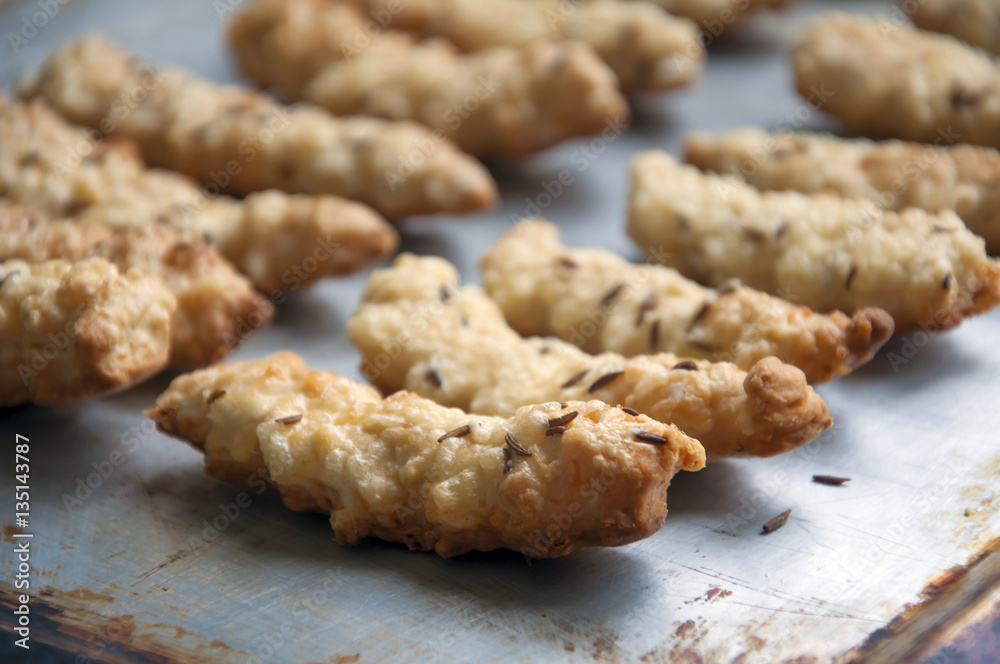 Homemade cookies with cheese and caraway seeds on a metal baking sheet close-up. Homemade cookies with cheese and caraway seeds on a metal baking sheet close-up.