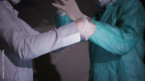 Nurse helps the doctor to put on white medical gloves photo