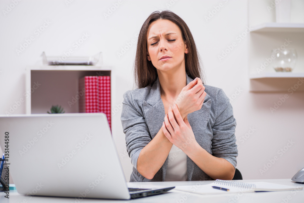 Young businesswoman is having pain in her arm at work. Young businesswoman is having pain in her arm at work.