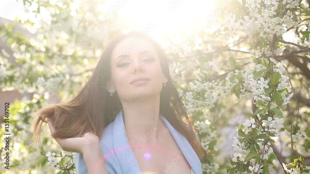 Young attractive girl smelling the cherry blossoms in spring. She enjoys the spring mood. Young attractive girl smelling the cherry blossoms in spring. She enjoys the spring mood.