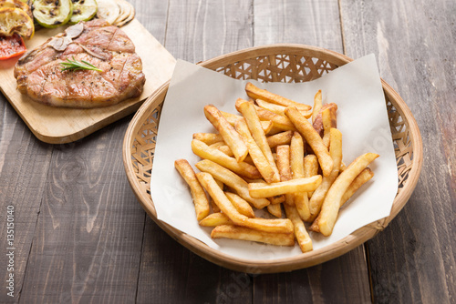 Chips and grilled pork chop on the wooden background