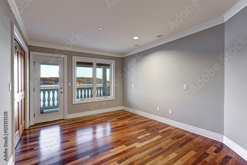 Empty room with hardwood floor and door to balcony.