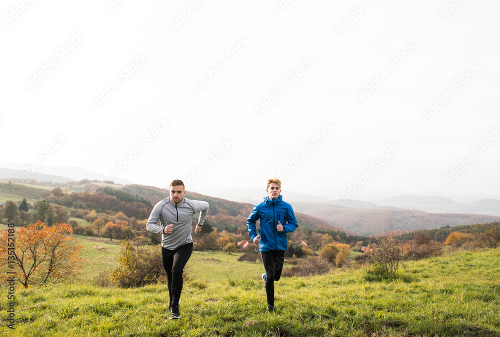 Two young hipster athletes running in sunny autumn nature Two young hipster athletes running in sunny autumn nature