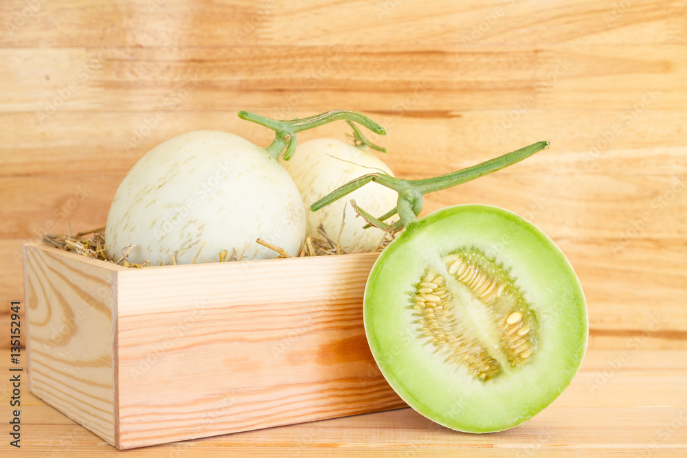 Green cantaloupe melon in wood box Green cantaloupe melon in wood box