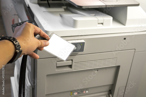 man hand hold card for scanning key card to access  Photocopier . Security system concept.