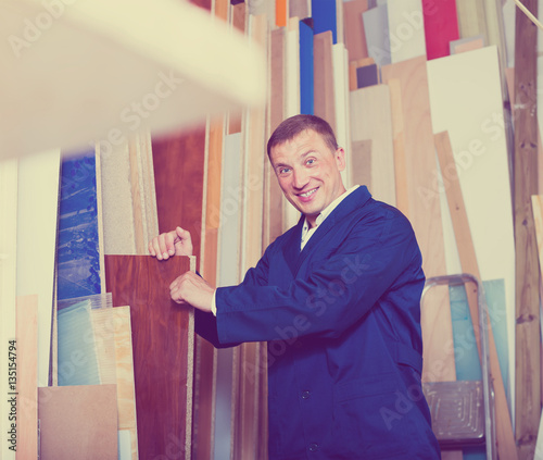 happy workman standing with plywood pieces photo