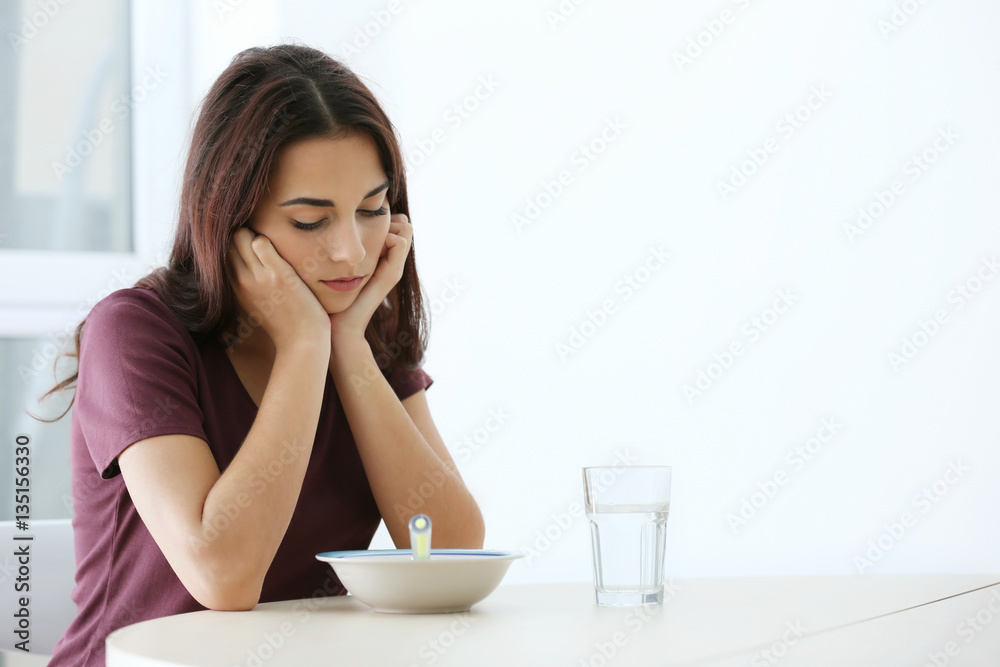 Depressed woman sitting at kitchen table without appetite Depressed woman sitting at kitchen table without appetite