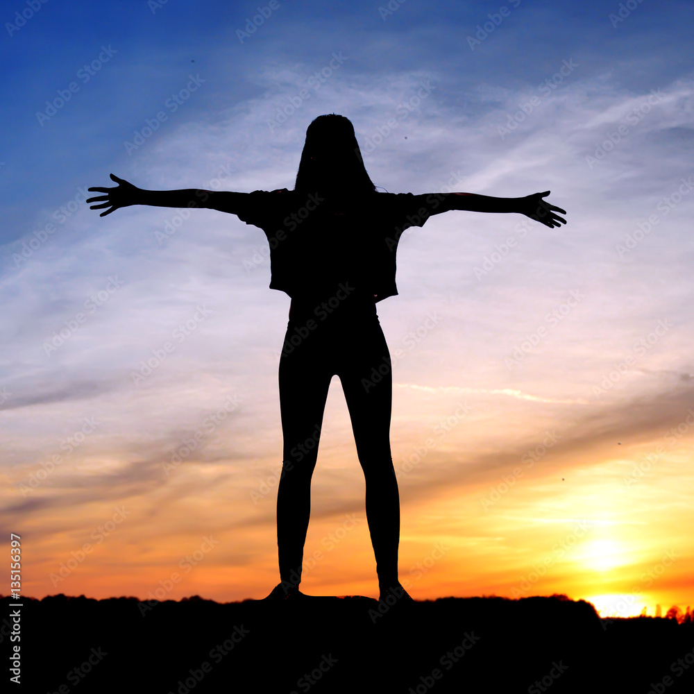 Free happy woman raising arms watching the sun in the background ...