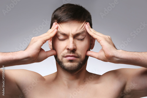 Young man with headache on color background