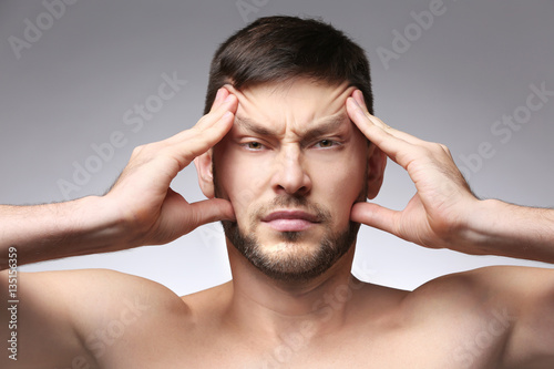 Canvas Print Young man with headache on color background