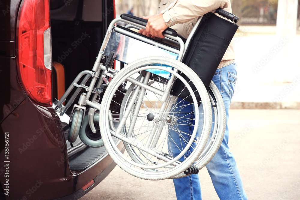 Man loading wheelchair of handicapped person Man loading wheelchair of handicapped person