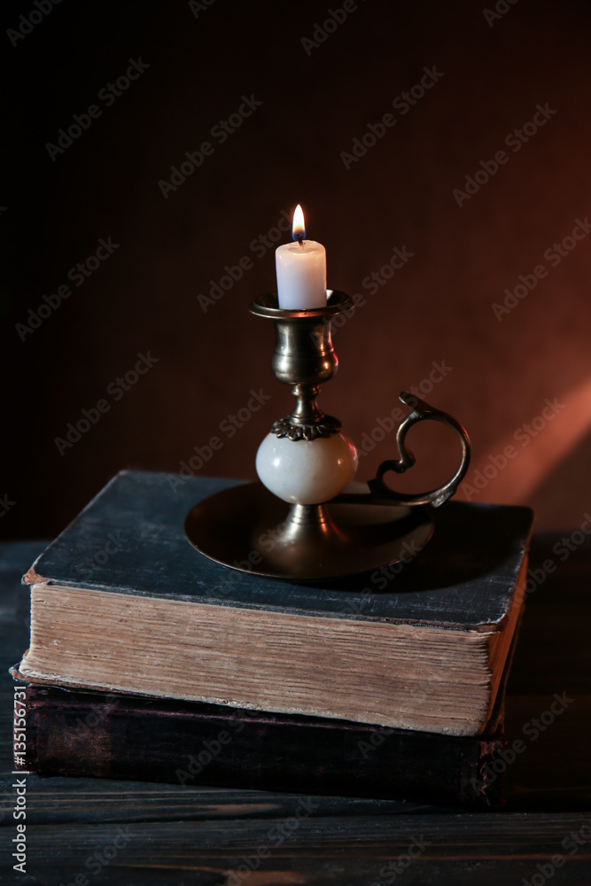 Bible with burning candle on wooden table