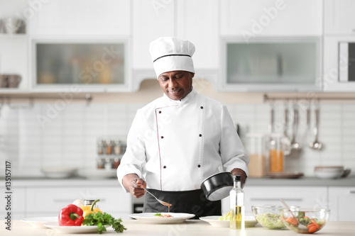Obraz na plátně Mature Indian chef cooking in kitchen