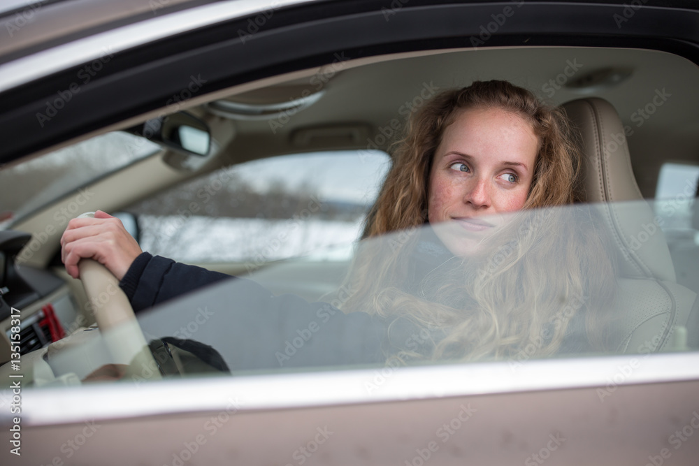 Pretty young woman driving her new car