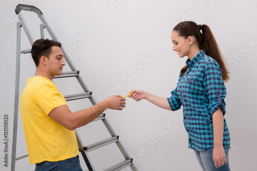 Young couple painting wall at home