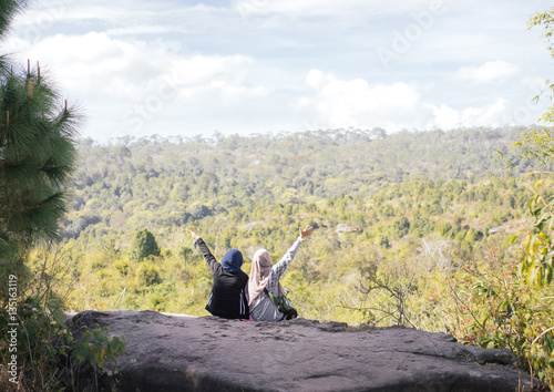 two muslim girl sit on rock