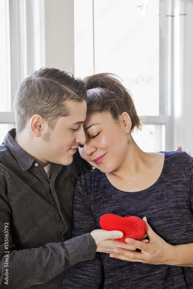 Latin couple of lovers hugging and holding Heart toy in Valentin