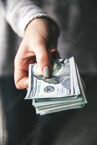 A stack of money, dollars in beautiful female hands. With a beautiful manicure. Business offer. Modern fashion.