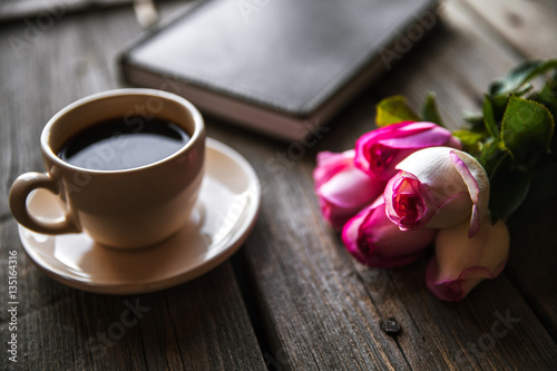 Fresh roses with diary and cup of coffee on wooden table, top view. flowers, hot drink