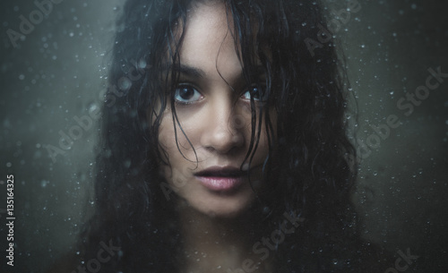 Billede på lærred Girl staring through rainy glass