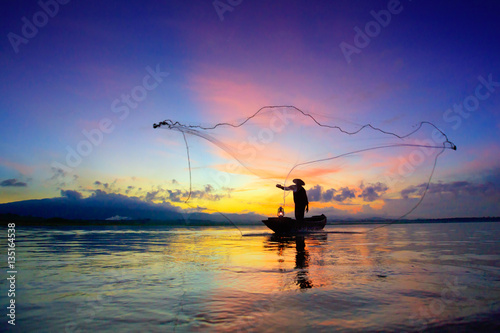 Silhouette of fishermen using nets to catch fish at the lake in the morning