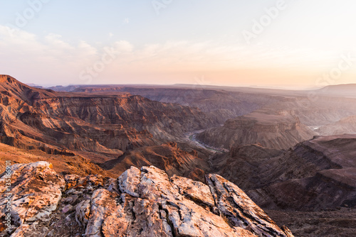 Fish River Canyon, scenic travel destination in Southern Namibia. Last sunlight on the mountain ridges. Wide angle view from above.