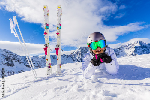 Girl with ski laying on the fresh snow on top of the mountain sk photo