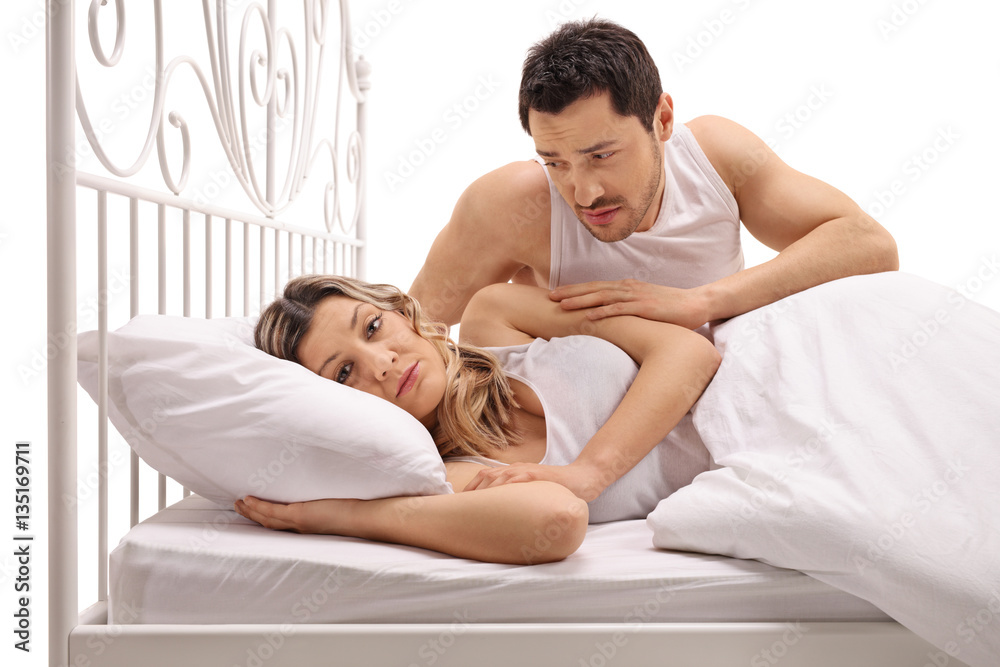 Unhappy woman in bed with concerned guy comforting her Unhappy woman in bed with concerned guy comforting her
