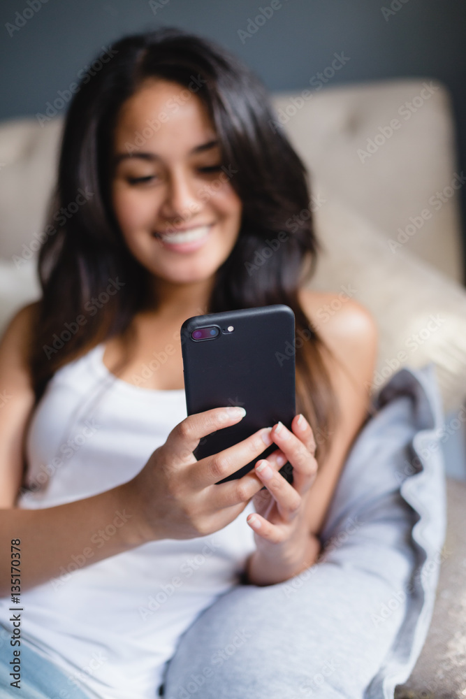 Teen girl using cellphone one bed Teen girl using cellphone one bed