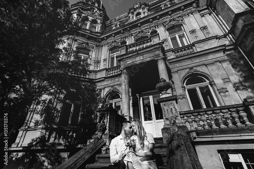 Look from below at tender wedding couple sitting on stone footst