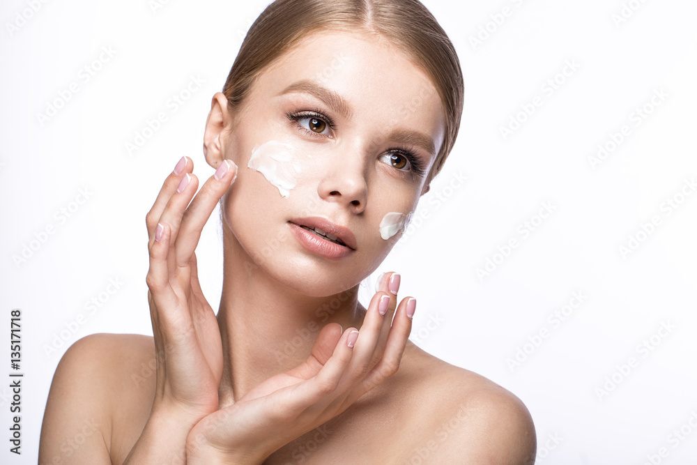 Beautiful young girl with cream on the skin and French manicure. Beauty face. Picture taken in the studio on a white background. Beautiful young girl with cream on the skin and French manicure. Beauty face. Picture taken in the studio on a white background.