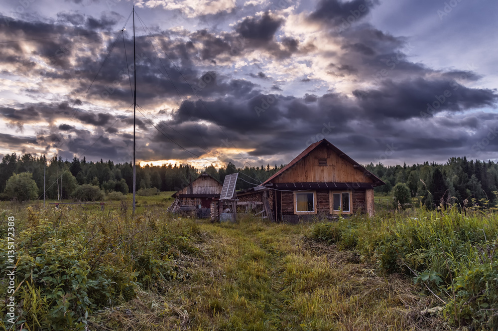 hut on the background of the sunset sky, clouds, forest in the b