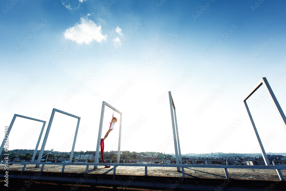 Beautiful aerial dancer, silk dance on roof at sunrise