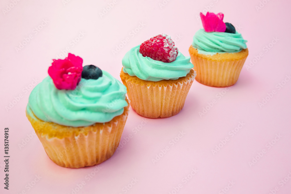 Cupcakes with butter cream and vanilla with raspberry on pink background Cupcakes with butter cream and vanilla with raspberry on pink background