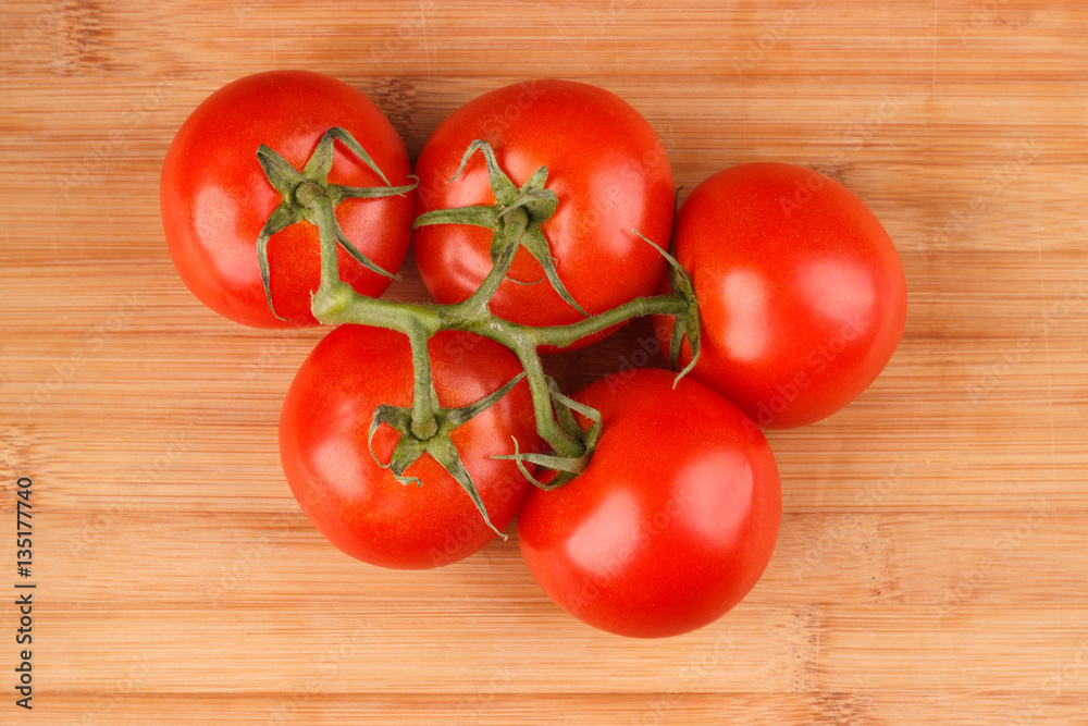 Bunch of red fresh raw tomatoes on the wooden board Bunch of red fresh raw tomatoes on the wooden board