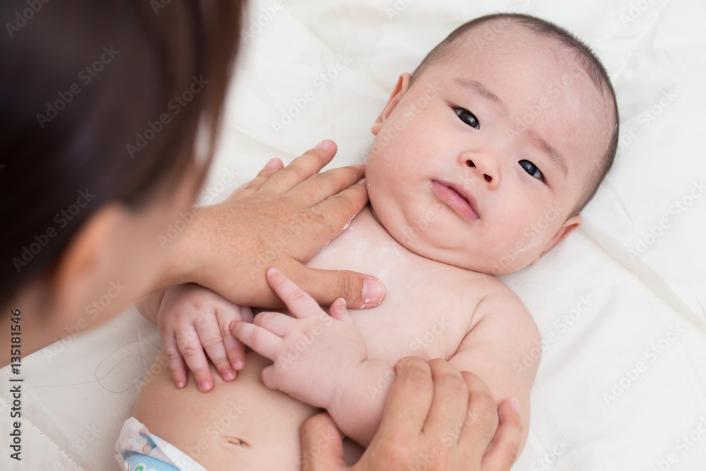 Mother applying baby powder for son Mother applying baby powder for son