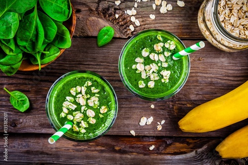 Green smoothie with spinach, banana and oatmeal on a wooden background. top view