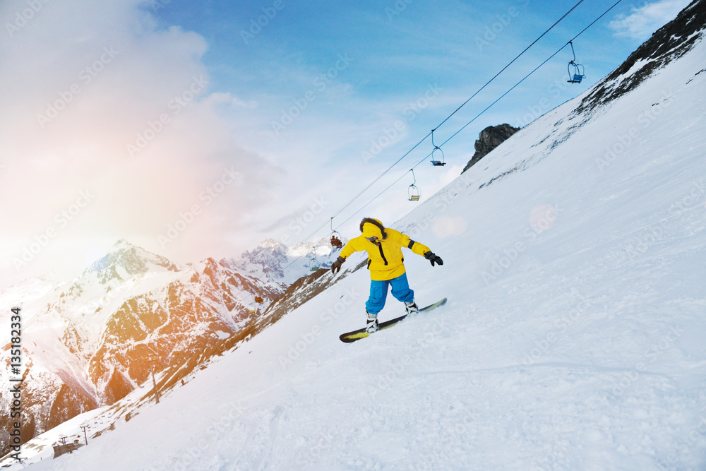 Man rides his snowboard on ski slope in winter mountains, in ski resort